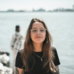 woman in black crew neck t-shirt wearing brown framed eyeglasses standing on rocky shore during
